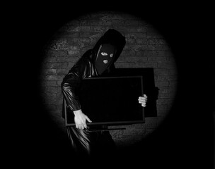 masked thief with tv on black background