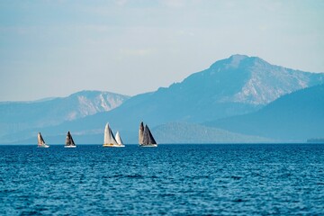 Beautiful view of sailboats sailing in the ocean and mountain in the background