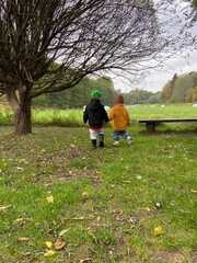 Fototapeta premium View of cute children playing in a green field on a cloudy day