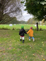 Fototapeta premium View of cute children playing in a green field on a cloudy day