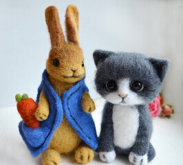 Knitted white cat with pink legs and yellow ribbon and white bunny in blue dress. Toy. Gift. Handmade