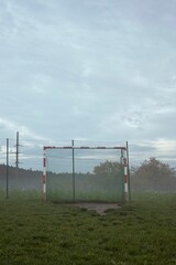Vertical view of a soccer goal in a fenced field on a rainy day