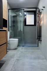 Vertical, front view of a modern shower cubicle with black steel profiles and porcelain floor.