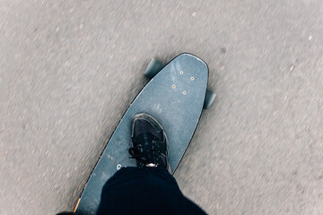 Top view of a person's leg on a skateboard on the process of riding on asphalt