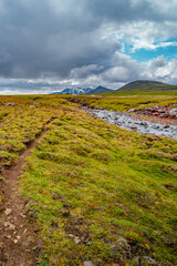 View over a highland glacial river and surreal volcanic landscape in Iceland, summer, with dramatic sky