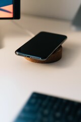 Shallow focus shot of a black mobile wireless charging on the table with electrical gadgets