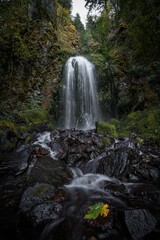 Vertical shot of the beautiful waterfall surrounded by dark mossy rocks.