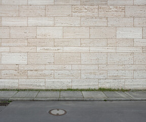 image of a tiled beige stone wall a sidewalk and a street as background, natural stone wall texture...