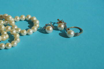 pearl jewelry, beads around the neck, a gold ring with pearls and earrings. women's necklace. background for the design.