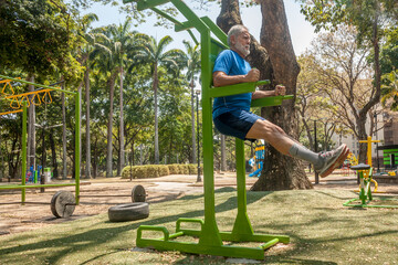 Mature man workout exercises in outdoor fitness park