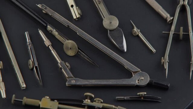 Compass for drawing. Set of old different compasses. Retro metal compasses and drafting tools on a black background. Drawing pen. Tool for study draw