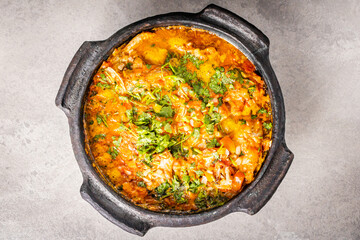 Delicious Brazilian fish moqueca with tomato, onion, olive oil, coriander and orocum seed. Made in clay pot on white table and black background.