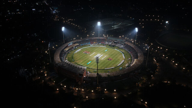 Illuminated Qaddafi Stadium's aerial view during the Pakistan Super League (PSL) cricket match with the crowd at night. 