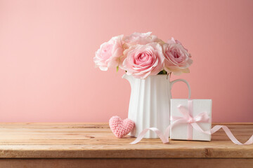 Happy Mother's day concept with rose flowers, heart shape and gift box on wooden table over pink background