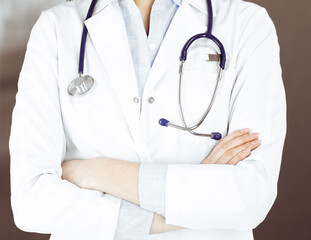 Unknown young woman doctor is standing with arms crossed in clinic. Medicine concept during...