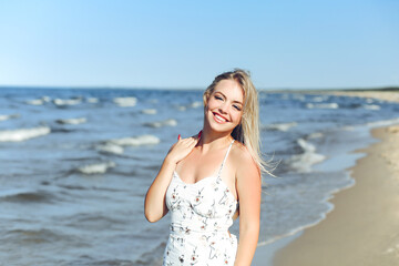 Fototapeta na wymiar Happy blonde woman in free happiness bliss on ocean beach standing straight and posing