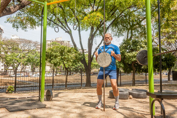 Fototapeta na wymiar Mature man workout exercises in outdoor fitness park
