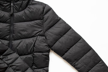 Black puffy winter jacket lies on a white background, fashionable winter clothes