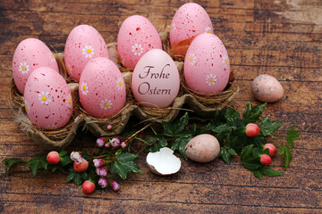 Osterkarte Frohe Ostern: Rosafarbene Ostereier in einer Eierschachtel mit der Aufschrift frohe...