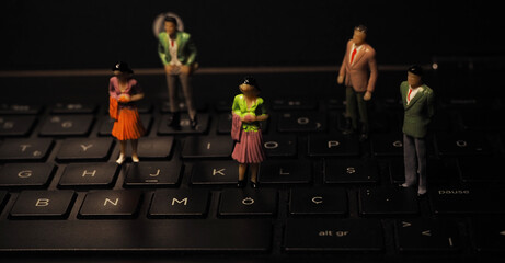 Group of miniature human figures of men and women on a notebook keyboard
