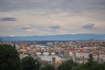 Fototapeta na wymiar Florence cityscape in a cloudy day with ponte vecchio and snowy mountains in background
