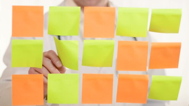A doctor in a white coat with a stethoscope sticks a note with handwritten words sport life on a transparent board with green and orange stickers. Promotion of a healthy lifestyle, fitness.