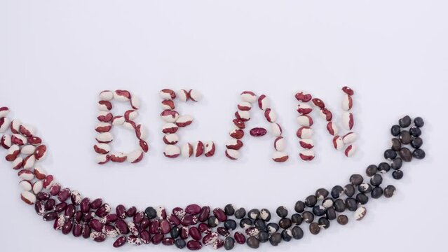 Out of pile of beans formed word bean with smile and, love crops, multicoloured seeds, agriculture, nutritious food, healthy diet, protein, vegetables. Close up, 4K Ultra HD.