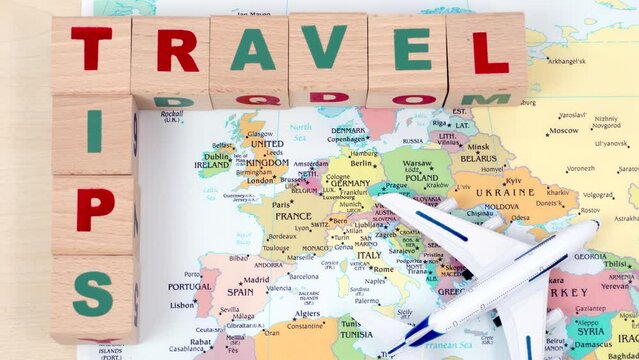 the wooden cubes make words travel tips on the map of europe and white plane flies over the map