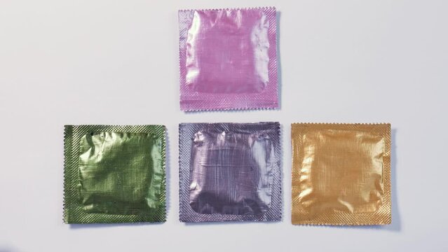 Women's hands impatiently grab multi-colored condoms. Passion, sexual relationship, love, safe sex.
