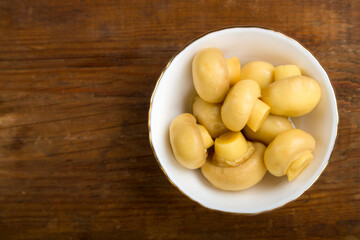 Champignon mushrooms in a white plate on a wooden table. save a place.