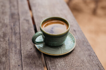 Hot Americano on the veranda. Hot black coffee in a green mug side view