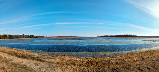 Early spring, river flood on agricultural meadows. Reflection in submerged fields covered by water. Seasonal overflow. Rural sunny Panorama. - 582537772