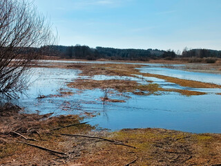 Early spring, river flood on agricultural meadows. Reflection in submerged fields covered by water. Seasonal overflow. Rural sunny Panorama.