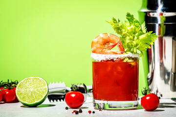 Bloody Caesar alcoholic cocktail drink, version of Bloody Mary with tomato juice, vodka, clam broth, celery, hot sauce and ice in glass garnished with salt. Green background, hard light