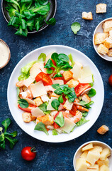 Caesar salad with shrimp, iceberg lettuce, croutons, parmesan cheese and tomatoes with caesar dressing. Blue table background, top view