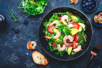 Strawberry, shrimp and herbs healthy salad with arugula, avocado and onion, blue kitchen table. Fresh useful dish for healthy eating