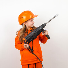 Little girl in an orange suit and construction helmet, holding puncher, concept of young worker. Portrait, child builder, white background, Labor Day.