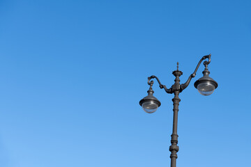 Fototapeta na wymiar Close-up view of black ornate street lamppost with led lamps standing against clear blue sky in the morning. Copy space for your text. Soft focus. City life theme.