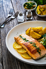 Fried salmon steak with lemon, fried potatoes and pak choi cabbage served on wooden table
