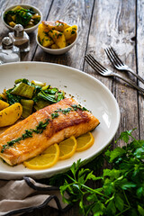 Fried salmon steak with lemon, fried potatoes and pak choi cabbage served on wooden table
