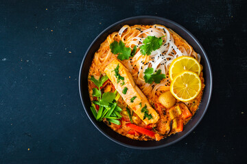 Tom Yum - Thai soup with salmon and rice noodles on wooden table
