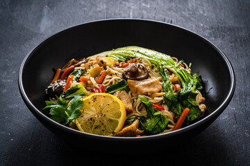 Asian food - chicken nuggets, noodles, stir fried vegetables, soy sauce, pak choi cabbage  and shiitake mushrooms on wooden table
