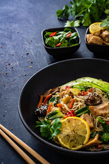 Asian food - chicken nuggets, noodles, stir fried vegetables, soy sauce, pak choi cabbage  and shiitake mushrooms on wooden table

