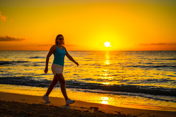 Beach holiday - beautiful woman walking, running on sunny, tropical beach in the morning
