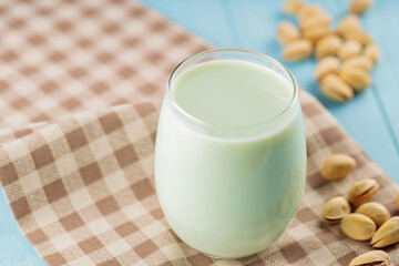 Pistachio milk in glass on blue boards. Vegan nutty plant based milk. Diet milk, vegetarian food