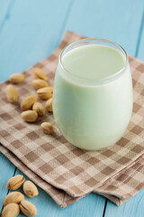 Pistachio milk in glass on blue boards. Vegan nutty plant based milk. Diet milk, vegetarian food