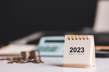 Small 2023 year calendar on desk with financial management background. concept of planning and...