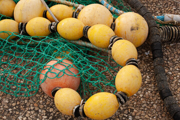Green fishing nets with its yellow buoys. A fishing net is placed on the ground with its yellow...