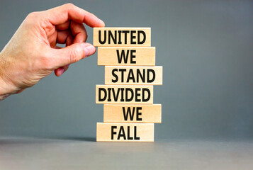 United or divided symbol. Concept words United we stand divided we fall on wooden blocks. Beautiful grey table grey background. Businessman hand. Business united or divided concept. Copy space.