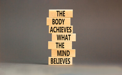 Mind and body symbol. Concept words The body achieves what the mind believes on wooden blocks. Beautiful grey table grey background. Copy space. Motivational mind and body concept.